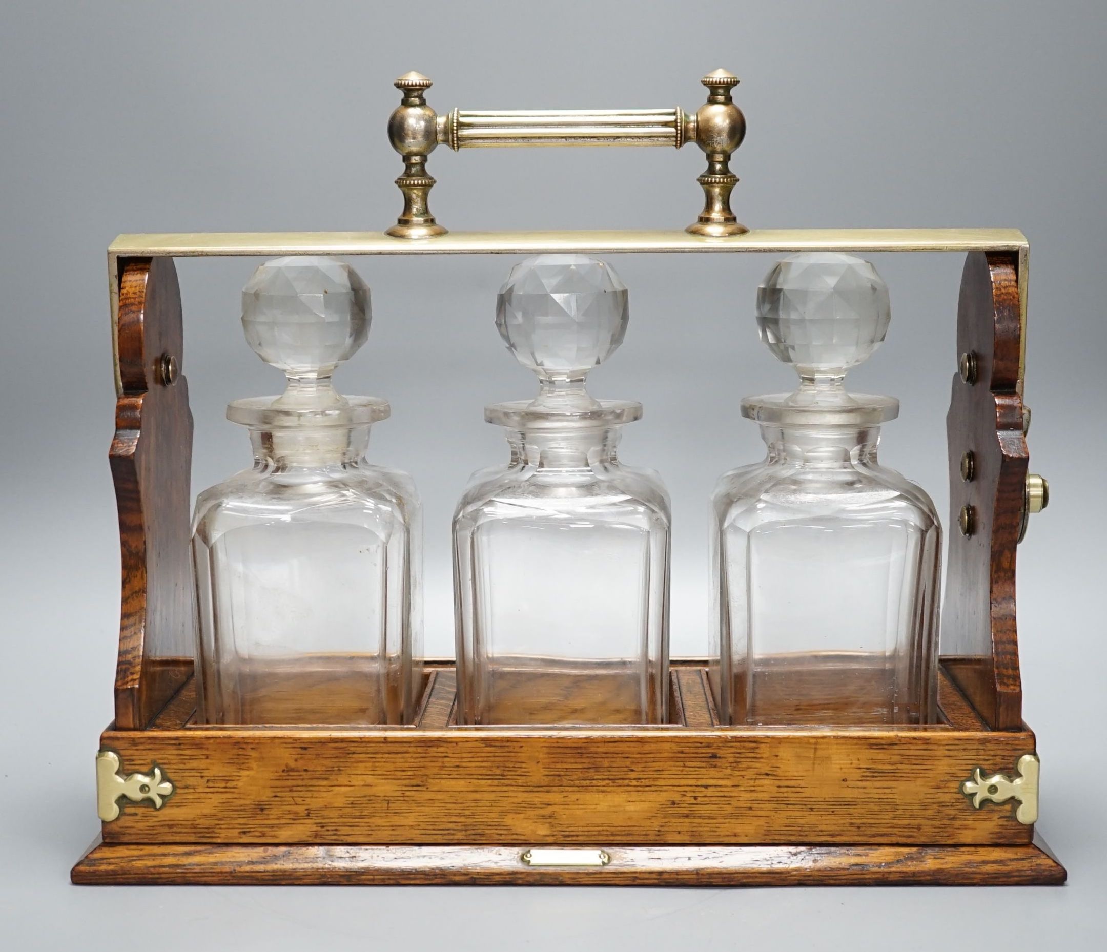 A Victorian Betjemann Patent oak three-bottle Tantalus - 34.5cm high